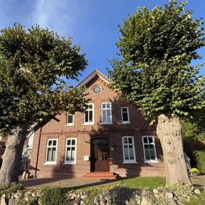 une maison en briques avec deux arbres devant elle dans l'établissement NEU! Ferienwohnung Zwei Linden, à Uthlede