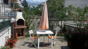 a table and chairs with an umbrella and a oven at La Montanara Apartment in Castel di Sangro