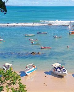 a group of boats in the water on a beach at Flats Mundos Golfinhos in Pipa