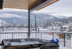 a hot tub on a balcony with a snowy mountain at Qs Hideaway in Mackenzie Village in Revelstoke