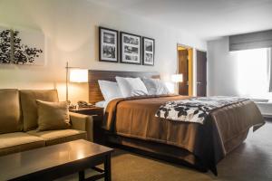 a hotel room with a bed and a couch at Sleep Inn & Suites East Syracuse in East Syracuse