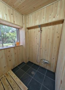 een badkamer met een douche in een houten muur bij Kaido Nomad CoLiving in Yuzawa