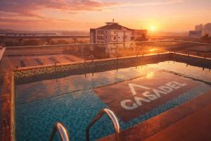 a swimming pool on the roof of a building with the sunset at Hotel Hanata Kochi in Cochin
