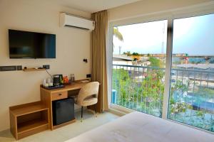 a bedroom with a bed and a desk and a large window at Hotel Hanata Kochi in Cochin