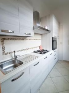 a white kitchen with a sink and a stove at Bilocale di Charme in Baronissi +1 photo