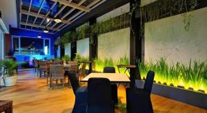 een restaurant met tafels en stoelen en planten aan de muur bij Atrium Premiere Cilacap in Cilacap