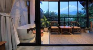 ein Bad mit einer Badewanne, einem Tisch und Stühlen in der Unterkunft Cocoa Valley Resort in Pua + 194 Fotos