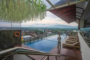 een man die bovenop een gebouw met een zwembad staat bij Java Lotus Hotel Jember in Jember