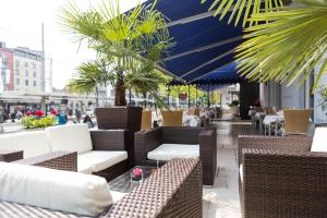 eine Terrasse mit Korbstühlen, Tischen und Palmen in der Unterkunft Hotel City Inn Basel in Basel