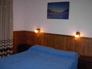 a bedroom with a blue bed and two lights on the wall at susana in La Falda