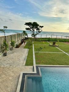 a swimming pool with a tennis court next to the ocean at Agni Luxury Beach Villa in Olagama