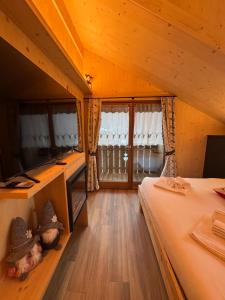 Zimmer mit einem Bett und einem TV in einer Hütte in der Unterkunft Appartamenti Casa Sabry in San Niccolò Comèlico