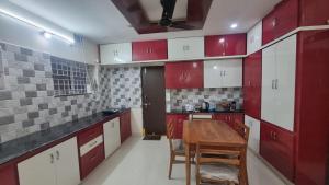 a kitchen with red and white cabinets and a wooden table at Kutir Stay Aaram in Secunderabad +16 photos