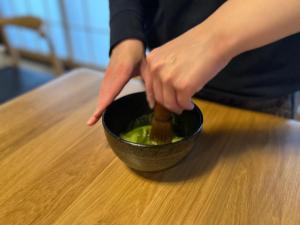 a person is stirring a bowl on a table at Japanese Traditional Inn Kamakura Rakuan in Kamakura