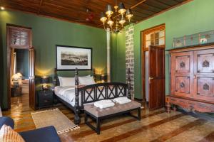 a bedroom with green walls and a bed with a bench at Garfield Bungalow by TONIK - 4BR Private Bungalow in Haputale - Mountain Views in Haputale
