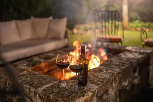 two glasses of red wine next to a fire pit at Garfield Bungalow by TONIK - 4BR Private Bungalow in Haputale - Mountain Views in Haputale