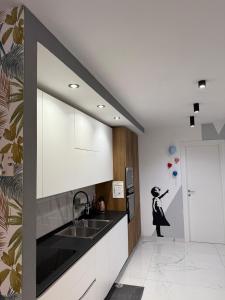 een keuken met witte kasten en een zwarte wastafel bij I MORI Alloggio turistico in Civitavecchia