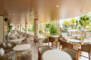 a restaurant with tables and chairs and a pool at Swiss-Grand Beach Resort Kuantan - Newly Upgraded 5-Star in Kuantan