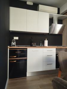 a kitchen with white cabinets and a black dishwasher at Casita acristalada con jacuzzi in Tiñosa Alta