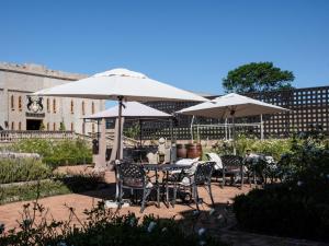 a patio with tables and chairs under umbrellas at Castle de Wildt in Modimolle