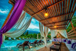 an outdoor patio with a pool with chairs and a roof at Levantes Villas in Kala Nera