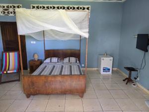 a bedroom with a wooden bed with a canopy at Chambre Bleu - Coco Room Nosy-Be in Nosy Be +4 photos