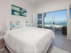 een witte slaapkamer met een groot bed en een groot raam bij Absolute Ocean Boutique Guesthouse in Hermanus +50 foto's