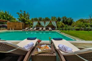 basen z wiklinowymi krzesłami i stołem oraz basen w obiekcie Levantes Villas w mieście Kala Nera