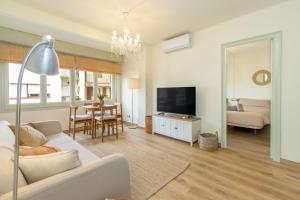 un salon avec un canapé blanc et une télévision dans l'établissement Calma de Mar en Palamós, à Palamós