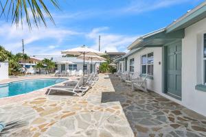 a pool with chairs and umbrellas next to a house at The Bungalows in St. Pete Beach