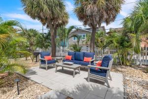 a patio with two blue chairs and a table and palm trees at The Bungalows in St. Pete Beach