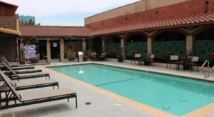 ein großes Schwimmbad mit Stühlen und einem Gebäude in der Unterkunft Alhambra Hotel in Alhambra