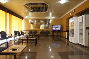 a waiting room with tables and chairs and a tv at Hotel Malibu in São Carlos