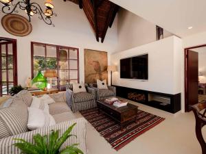 a living room with a couch and a tv at Yellowtail Finca in Plettenberg Bay