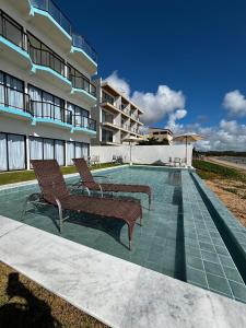 due sedie sedute accanto a una piscina di fronte a un edificio di Maraga Bento a Maragogi