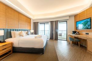 een hotelkamer met een groot bed en een bureau bij Swiss-Grand Beach Resort Kuantan in Kuantan