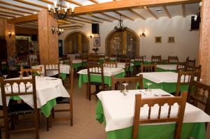 a restaurant with tables and chairs with green and white tables at Hotel Álvarez in Tuéjar