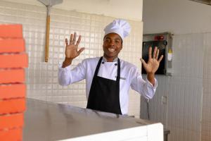 Ein Koch steht mit erhobenen Händen in der Küche. in der Unterkunft ZAN Paradise Jambiani Beach in Makunduchi + 79 Fotos