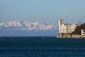 un castello in mezzo all'acqua con montagne di Residence Neverin Trieste a Trieste