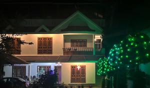 a house with a green christmas tree in front of it at Misty Morning Homestay in Thekkady