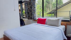 a bedroom with a white bed with a red pillow at 5BR Villa with Private Pool Lembang in Bandung +39 photos