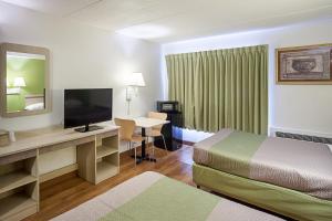 a hotel room with a bed and a desk with a television at Motel 6-Binghamton, NY in Binghamton