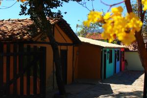 a building with colorful doors and a fence with yellow flowers at Pousada Vila Cipó in Serra do Cipo