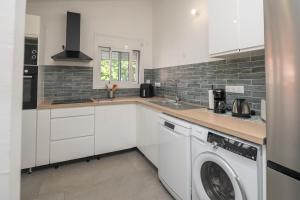 a kitchen with white cabinets and a washer at Villa Le Manguier - Logement Marcus, Tout Confort in Goyave