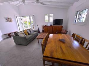 a living room with a wooden table and a couch at Villa Le Manguier - Logement Marcus, Tout Confort in Goyave +2 photos