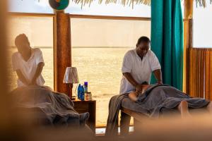 zwei Männer sitzen in Betten in einem Zimmer in der Unterkunft ZAN Paradise Jambiani Beach in Makunduchi