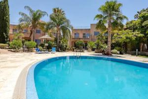 a large swimming pool with palm trees and a building at Large apartment in an idyllic complex, ocean view in Mandria