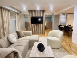 ein Wohnzimmer mit Sofa, Sesseln und Fernseher in der Unterkunft Södermalm City Flat in Stockholm