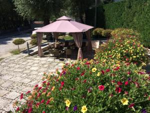 einen Tisch und einen Sonnenschirm in einem Garten mit Blumen in der Unterkunft Albergo Il Giardino del Rio in Castel di Sangro