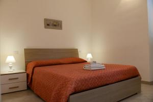 een slaapkamer met een bed met oranje lakens en 2 lampen bij GREGORIHOUSE in Anguillara Sabazia